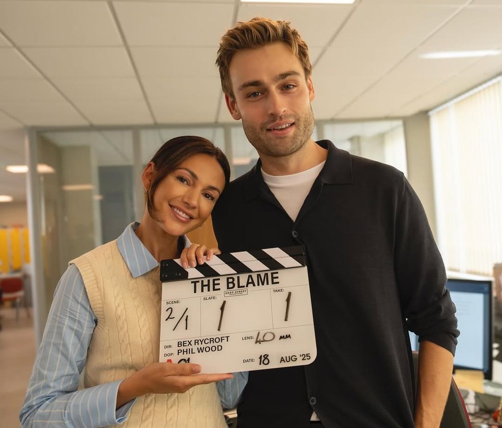 Two people stand holding a movie clapperboard