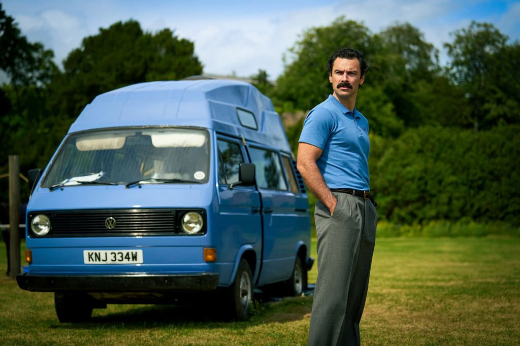 man in blue shirt standing next to camper van