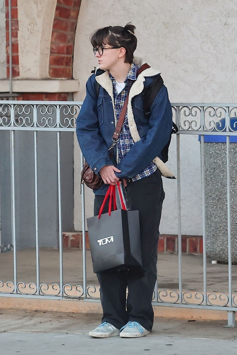 Fin Affleck was spotted in Brentwood playing on a computer near the Big Blue Bus stop, keeping it casual in a denim jacket, brown pants, and Adidas sneakers.