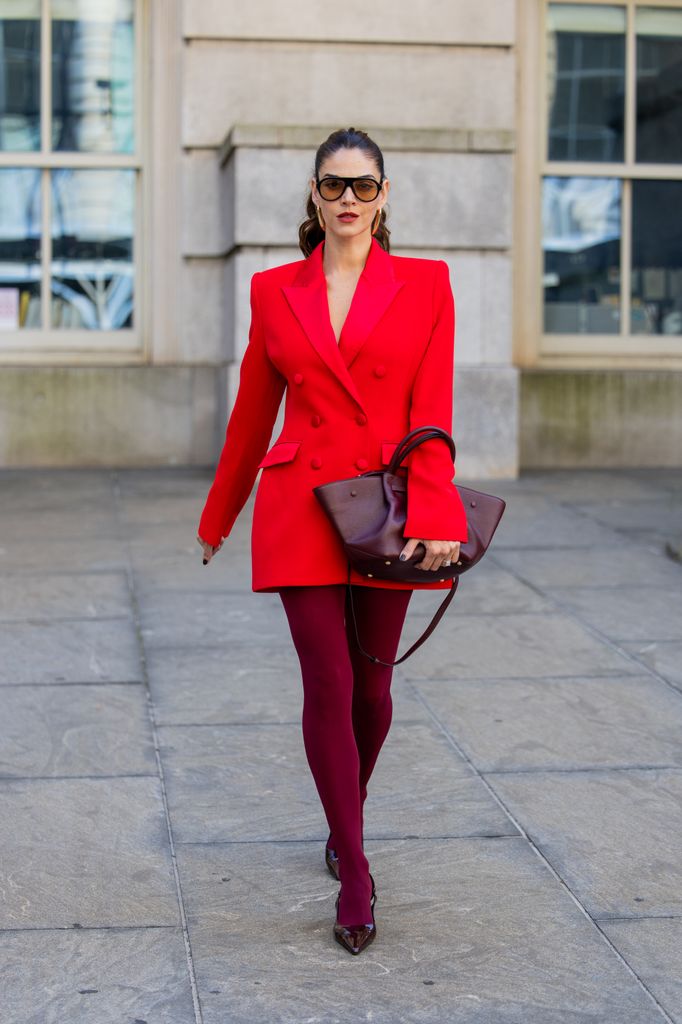 Jocelyn Osorio wears red Nadine Merabi blazer, bag Demellier London, Shoes Zara, glasses Elisa Johnson outside Alice & Olivia during New York Fashion Week on September 13, 2025 in New York City