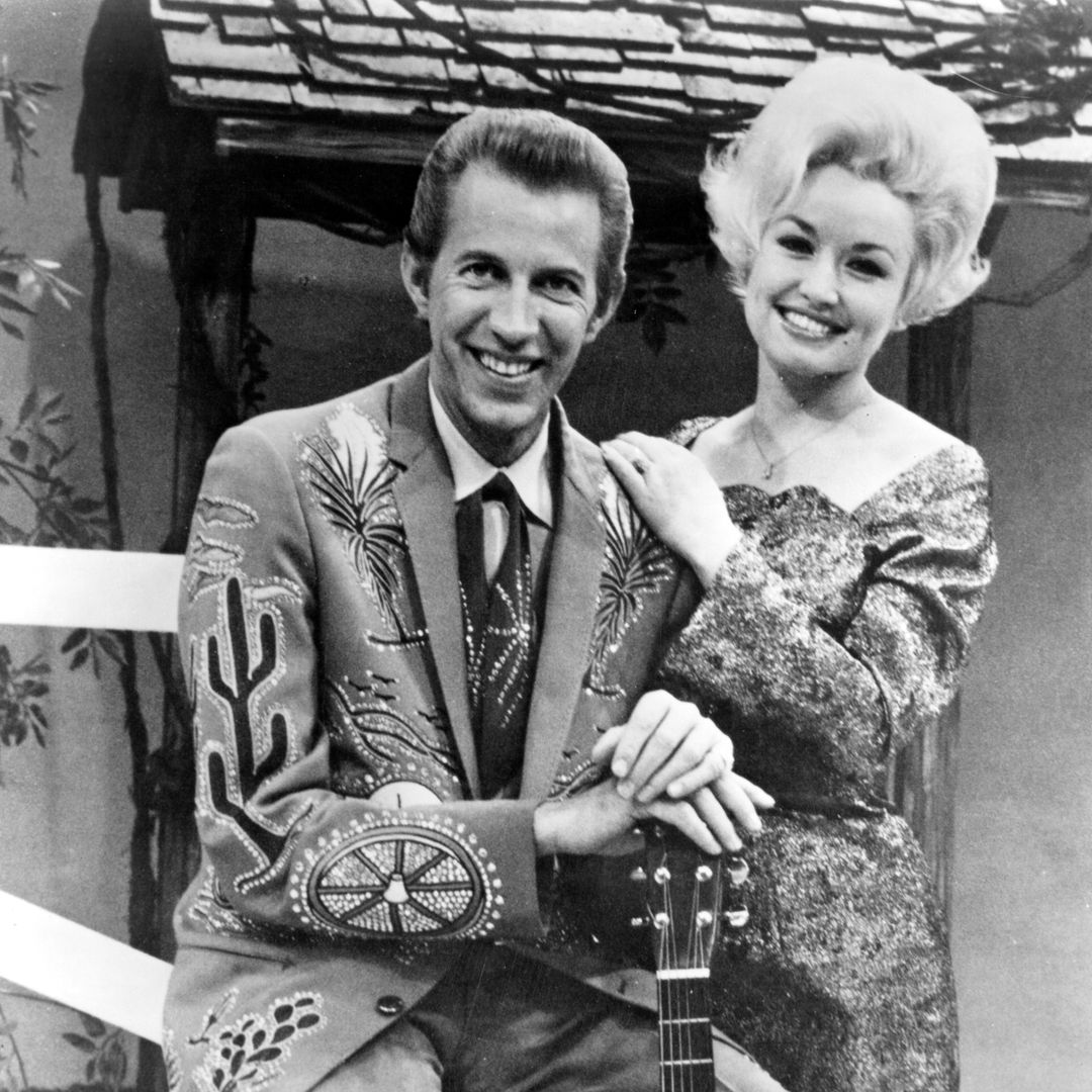 1967:  Country singer Dolly Parton with her collaborator Porter Wagoner on the set of his TV show in circa 1967. Mr. Wagoner is wearing a Nudie Suit designed by Nudie Cohn of Nudie's Rodeo Tailors.