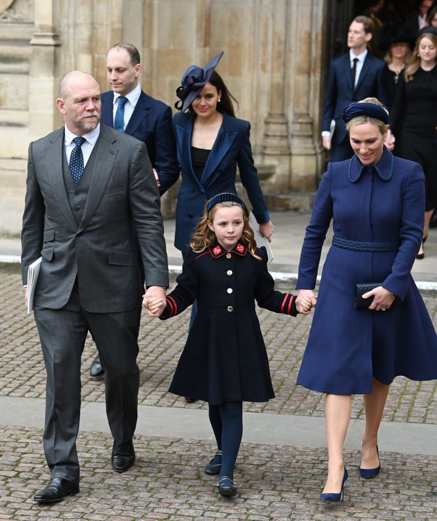 Mia in navy coat holding hands of mike and zara each side of her