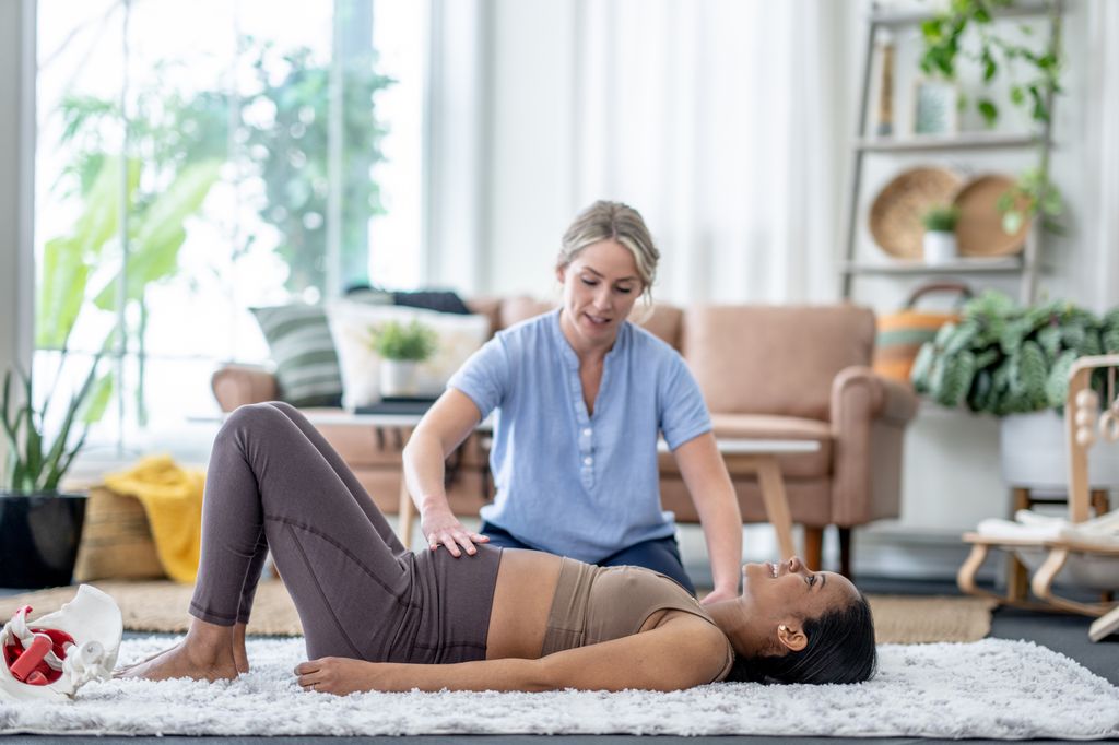 A female physiotherapist works with a pregnant woman on the floor