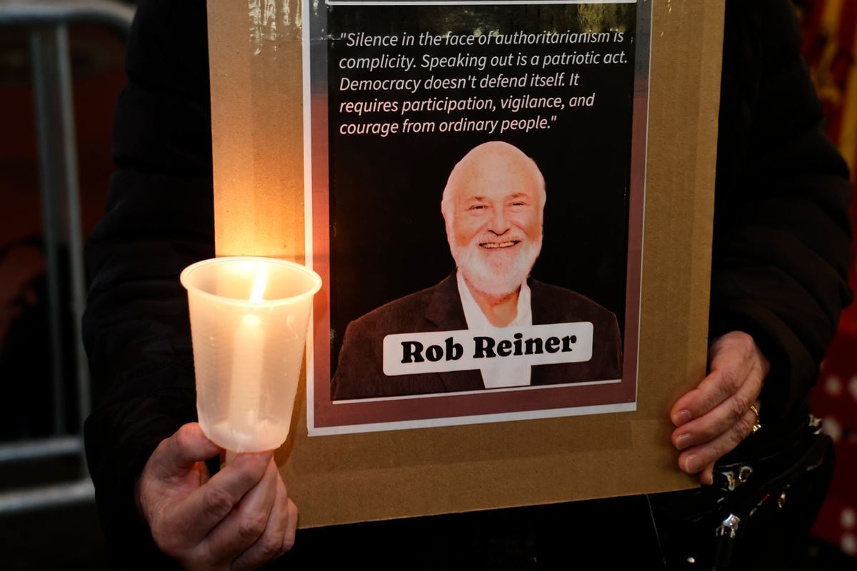An activist holds a sign during a vigil in memory of Rob Reiner 