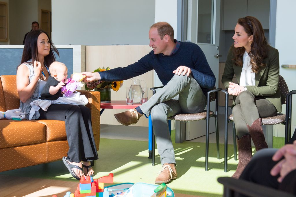 Kate wearing khaki jeans and cowboy boots sat beside william and woman holding baby