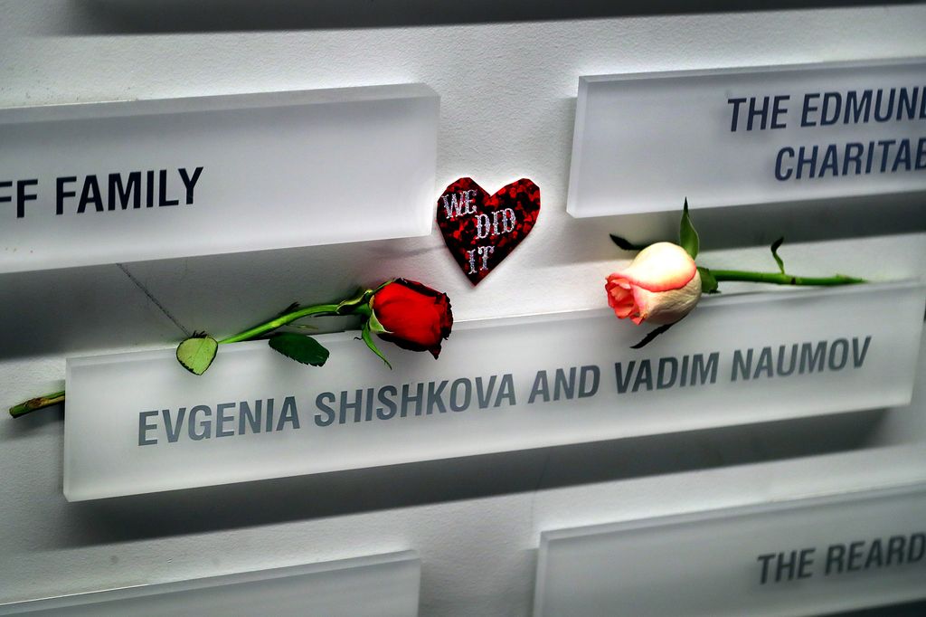 A heart that says "we did it" and flowers grace the name placard of the parents of Maxim Naumov on a wall at The Skating Club of Boston on January 14, 2026.
