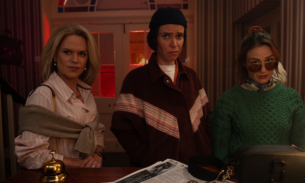three women standing at reception desk 