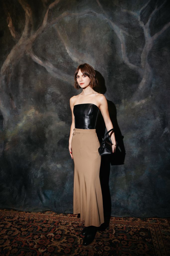Emilia Jones wears a leather strapless top and beige maxi skirt
