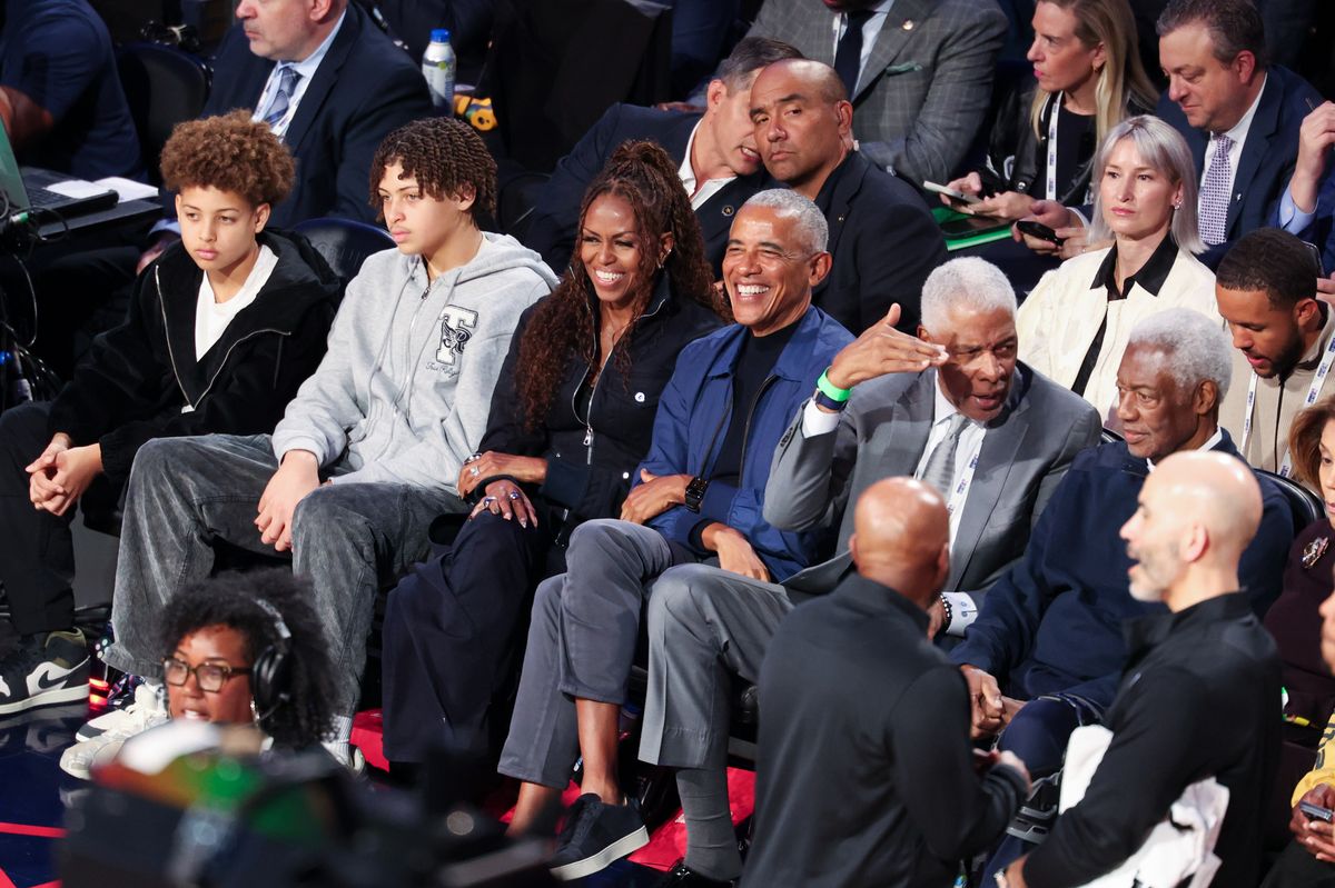 For the outing, Michelle embraced elevated courtside chic. She wore a sleek navy zip-up top layered over a fitted black look.