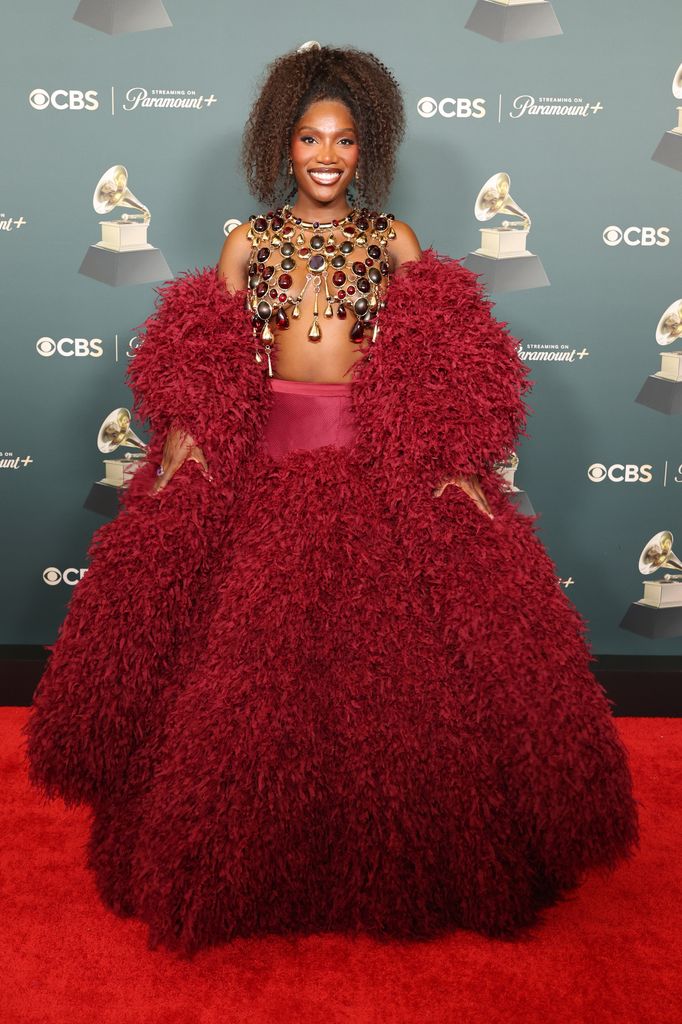 Doechii, winner of the Best Music Video award for "Anxiety", poses in the press room during the 68th GRAMMY Awards in a red feathered big skirt and matching jacket.