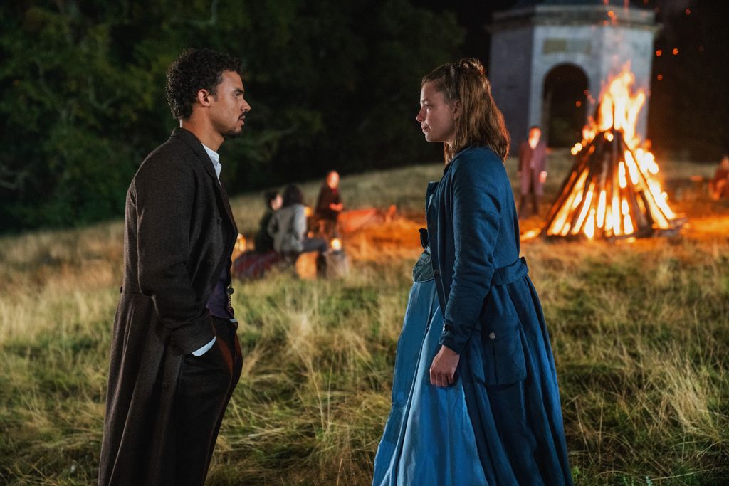 young man and woman looking at each other in front of bonfire