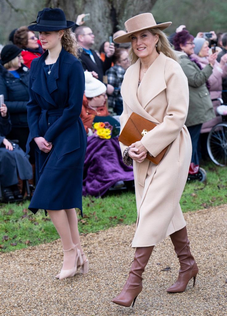 Sophie in neutral coat walking towarsd church with lady louise in navy