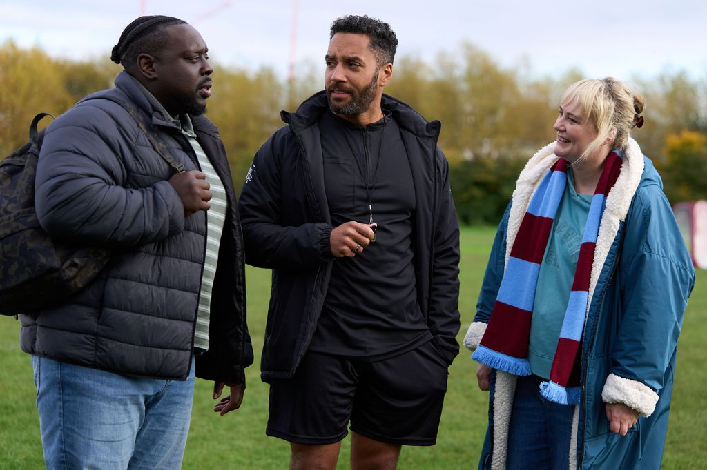 Three people standing on football field 