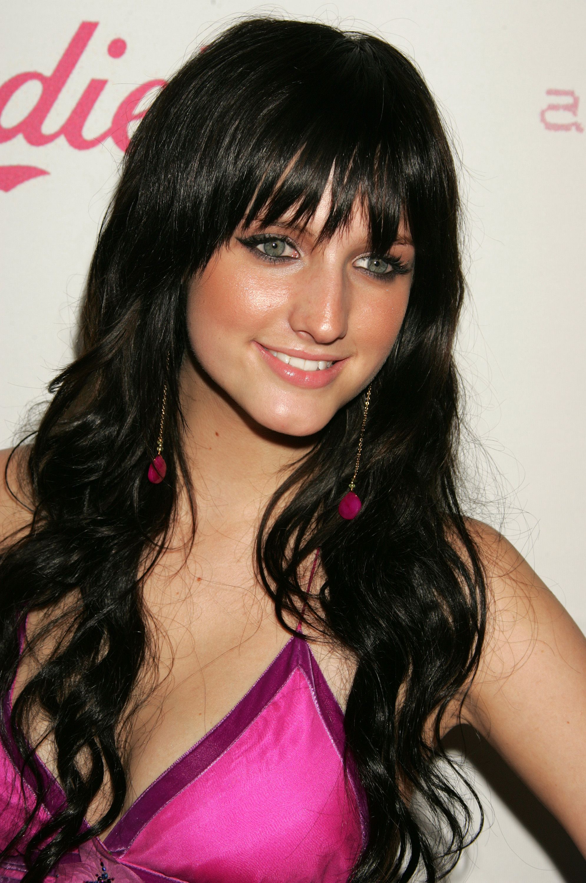 Ashlee Simpson smiling in a pink top with dark hair 