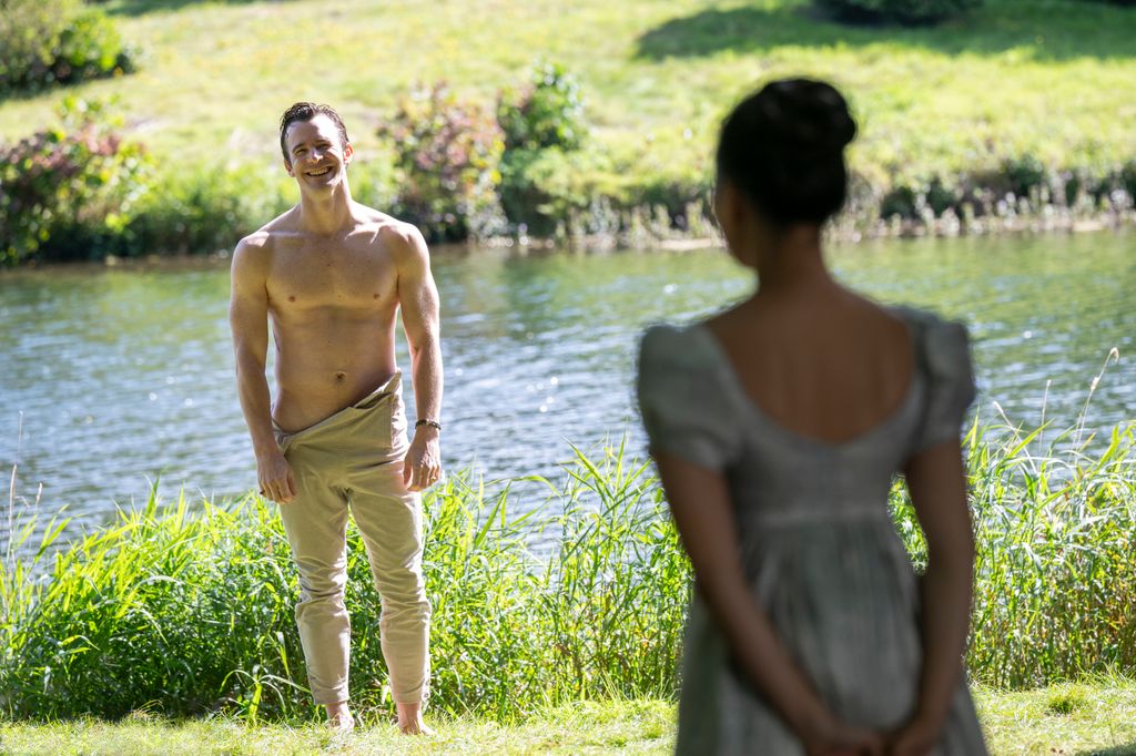 shirtless man standiing by lake