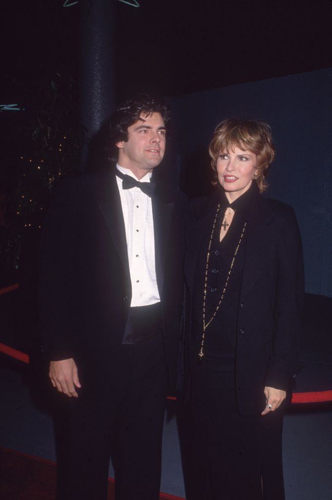Damon Welch wears a suit and tie while standing next to his mother, actress Raquel Welch.