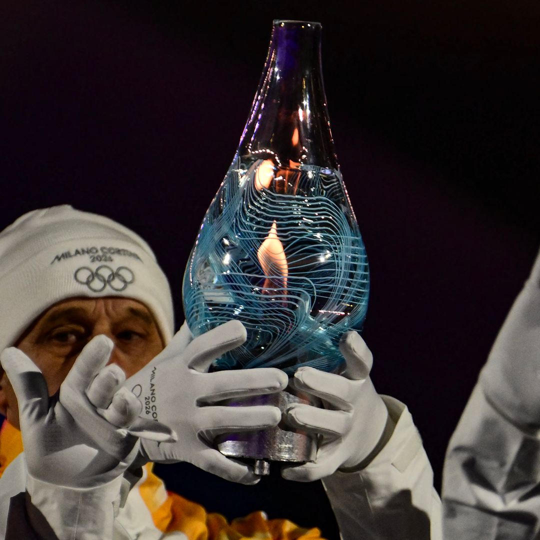 TOPSHOT - Italy's 1994 Winter Olympics 4Ã10km cross-country ski relay gold-medal winning team carry the Olympic flame within Murano glass during the closing ceremony of the Milano Cortina 2026 Winter Olympic Games at the Verona Arena in Verona, northern Italy, on February 22, 2026.