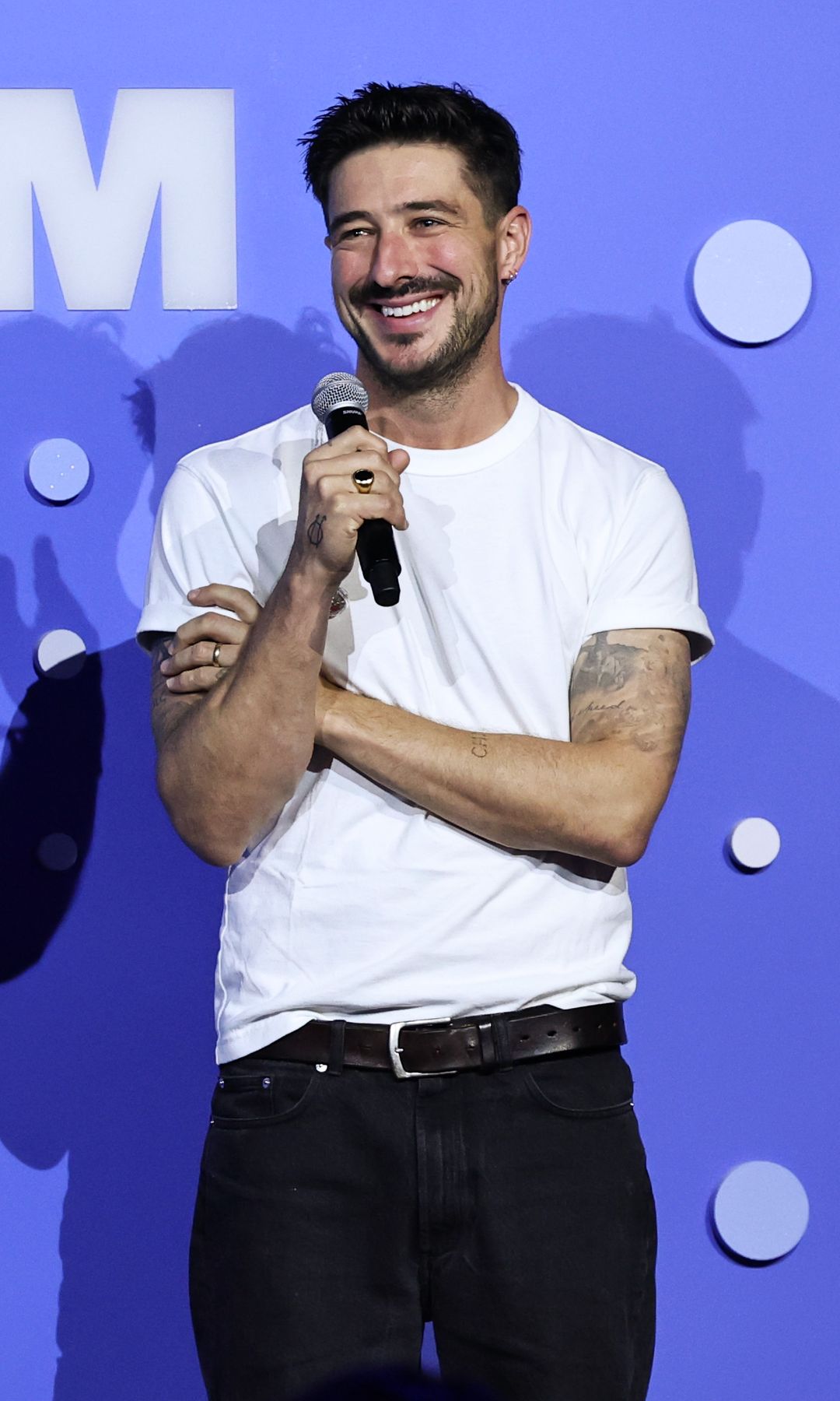 Marcus Mumford in a white t-shirt holding a microphone