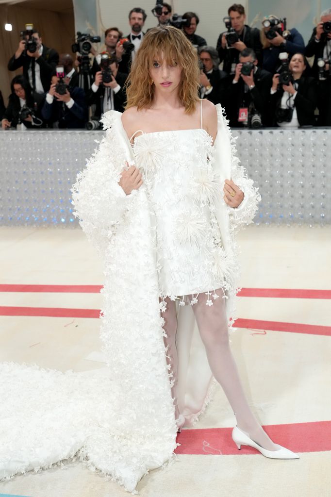 Maya Hawke posed in white mini dress and shawl jacket
