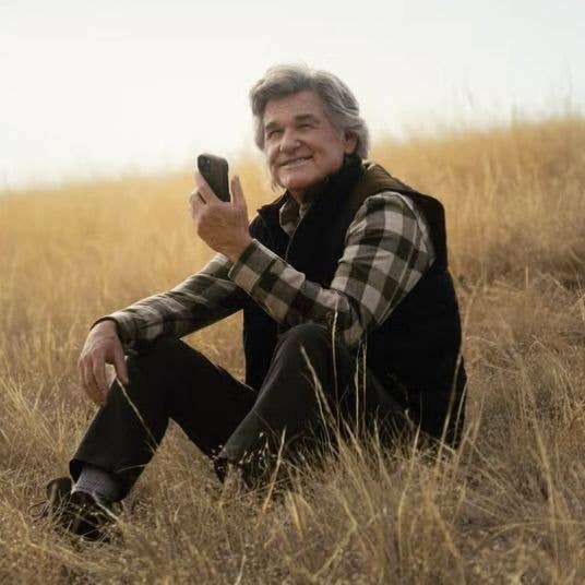 kurt russell sitting on the grass 
