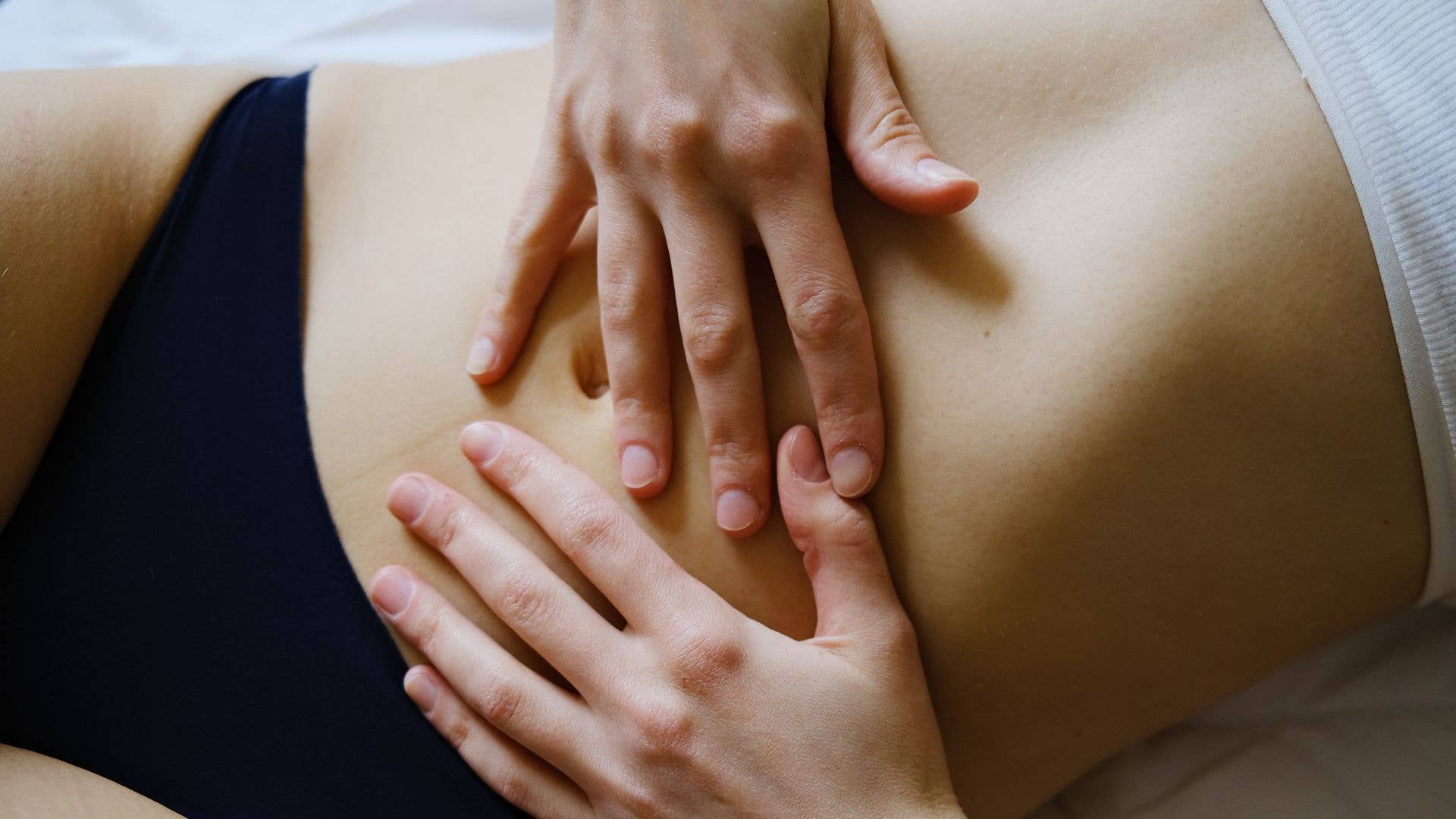 A picture of someone lying down with their hands on their stomach