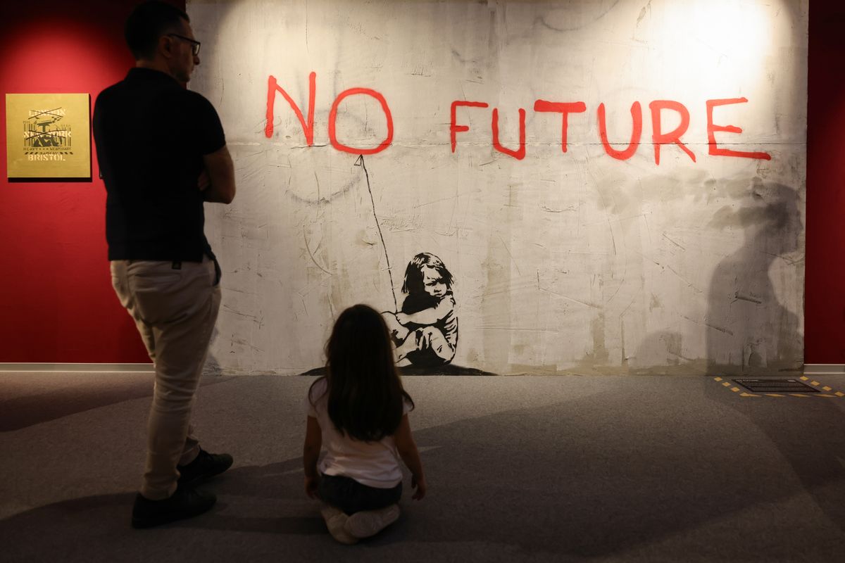  A child with her father stand in front of the Banksy work 'No Future' during the exhibition "The Mystery of Banksy - A Genius Mind" 