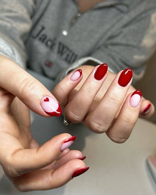 Symmetrical nail design with red heart accents on the thumbs.