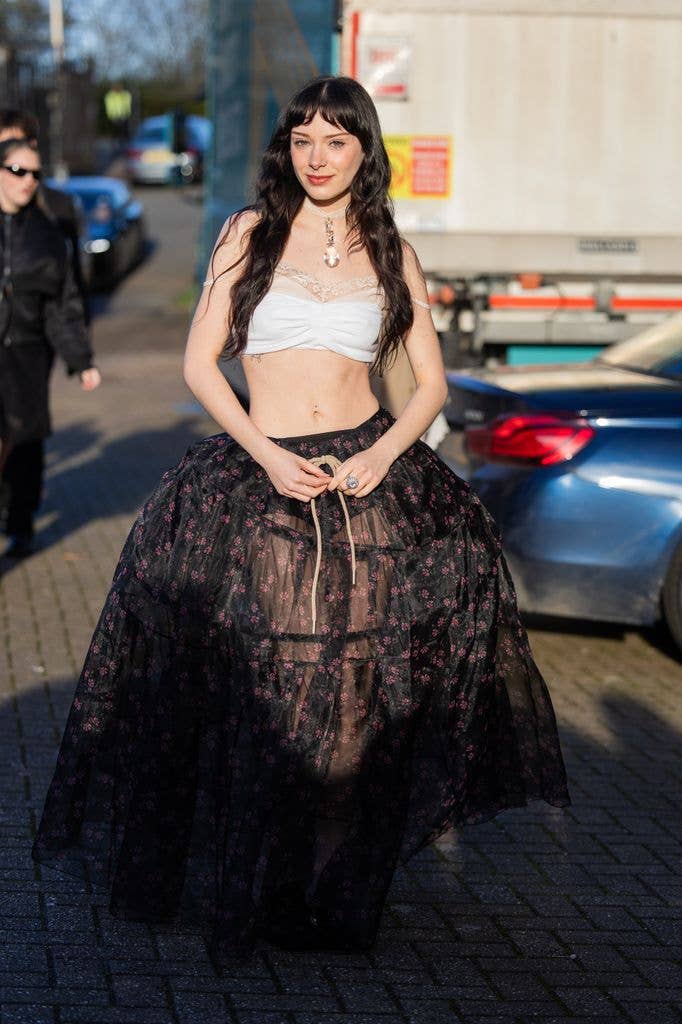 Holly Humberstone wears white cropped top, black wide transparent skirt outside Simone Rocha during London Fashion Week February 2026 