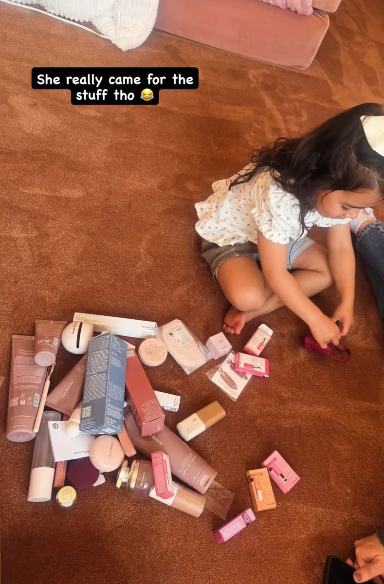 Aubriella sitting on the floor, surrounded by a dreamy spread of makeup and skincare goodies.