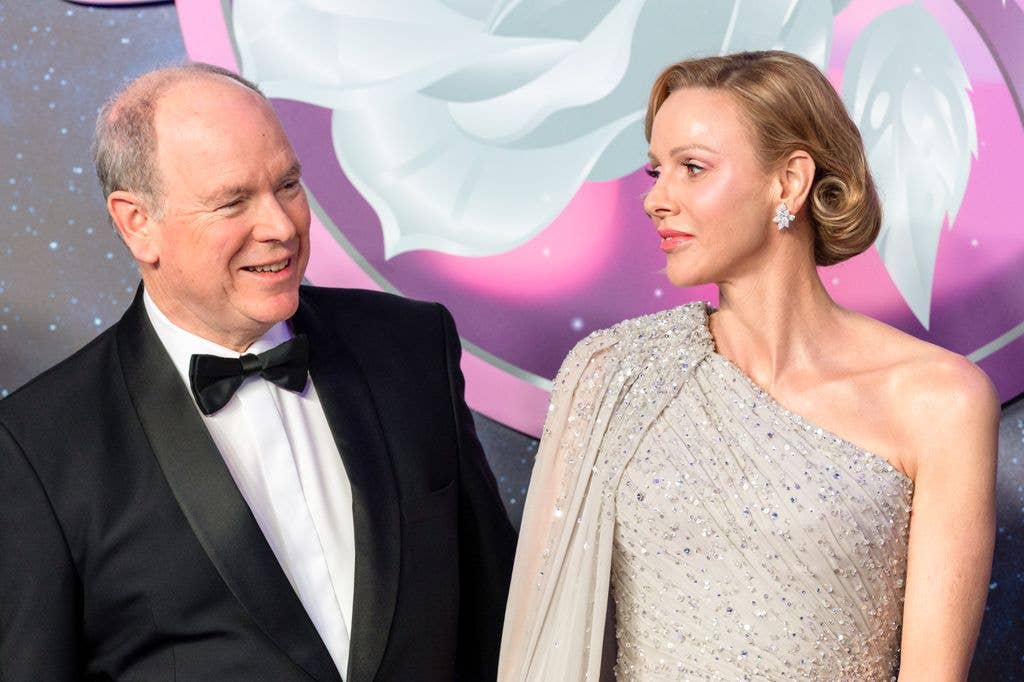 Princess Charlene in silver dress looking at albert in black tie