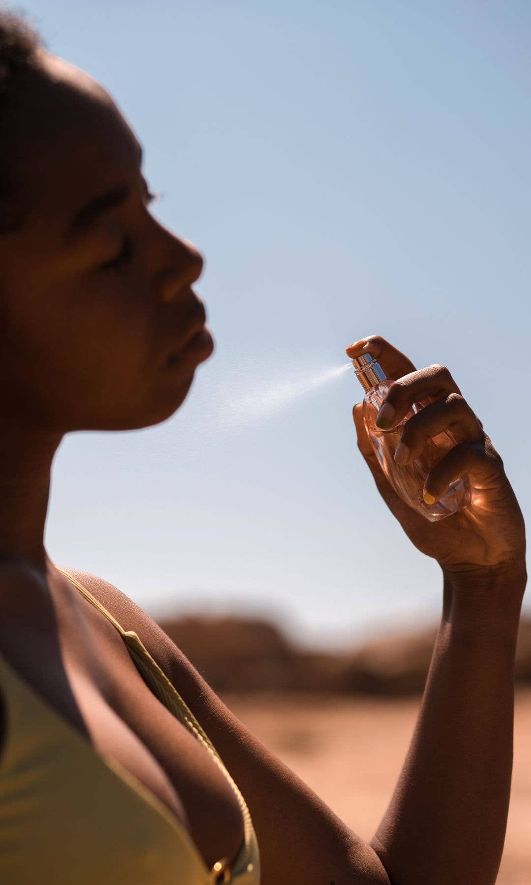 A woman spritzing perfume with her eyes closed