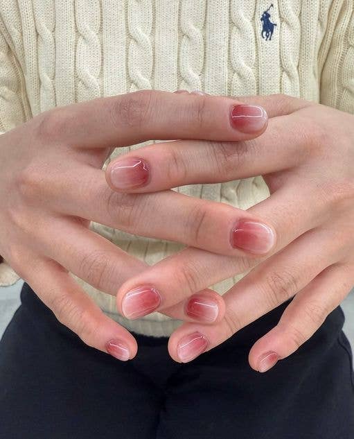 Sheer, strawberry-toned jelly nails with a high-shine, glass-like finish on a minimalist short manicure.