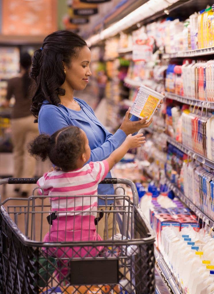 woman buying yogurt in supermarket with baby toddler