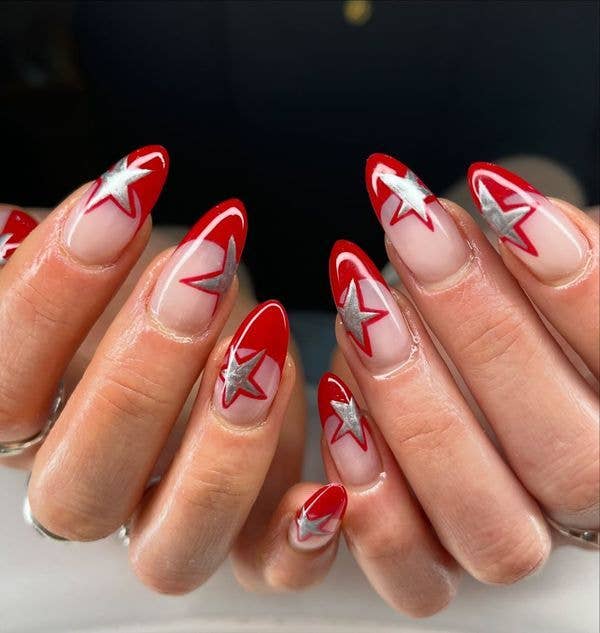 Star-shaped nail art in red and silver on almond-shaped nails.