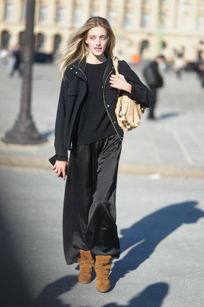 A person is seen wearing a black crewneck sweater, a black zip-up utility jacket, black wide-leg trousers, brown suede wedge sneakers, while carrying a beige leather shoulder bag during day two of Paris Fashion Week - Womenswear Fall/Winter 2026/2027 on March 03, 2026 in Paris, France. (Photo by 305pics/Getty Images)