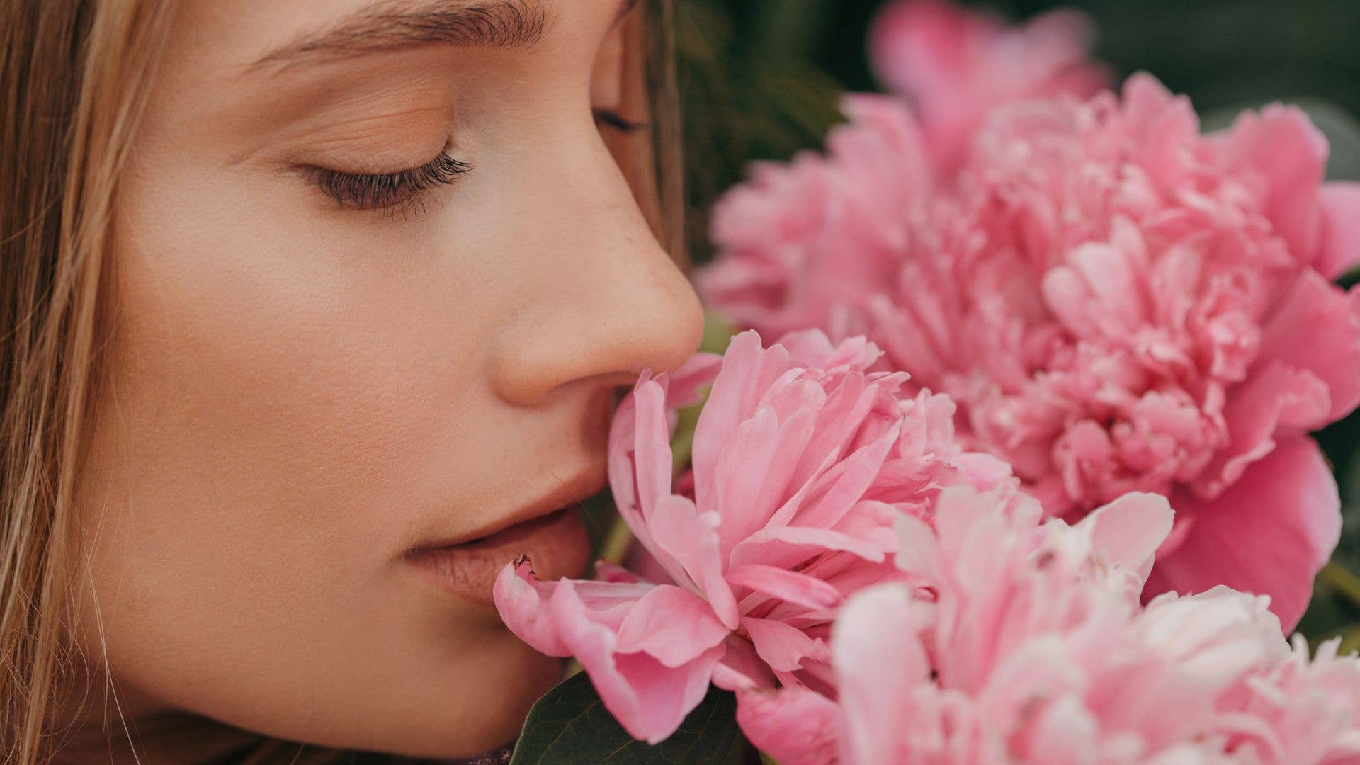 A model smelling large pink flowers