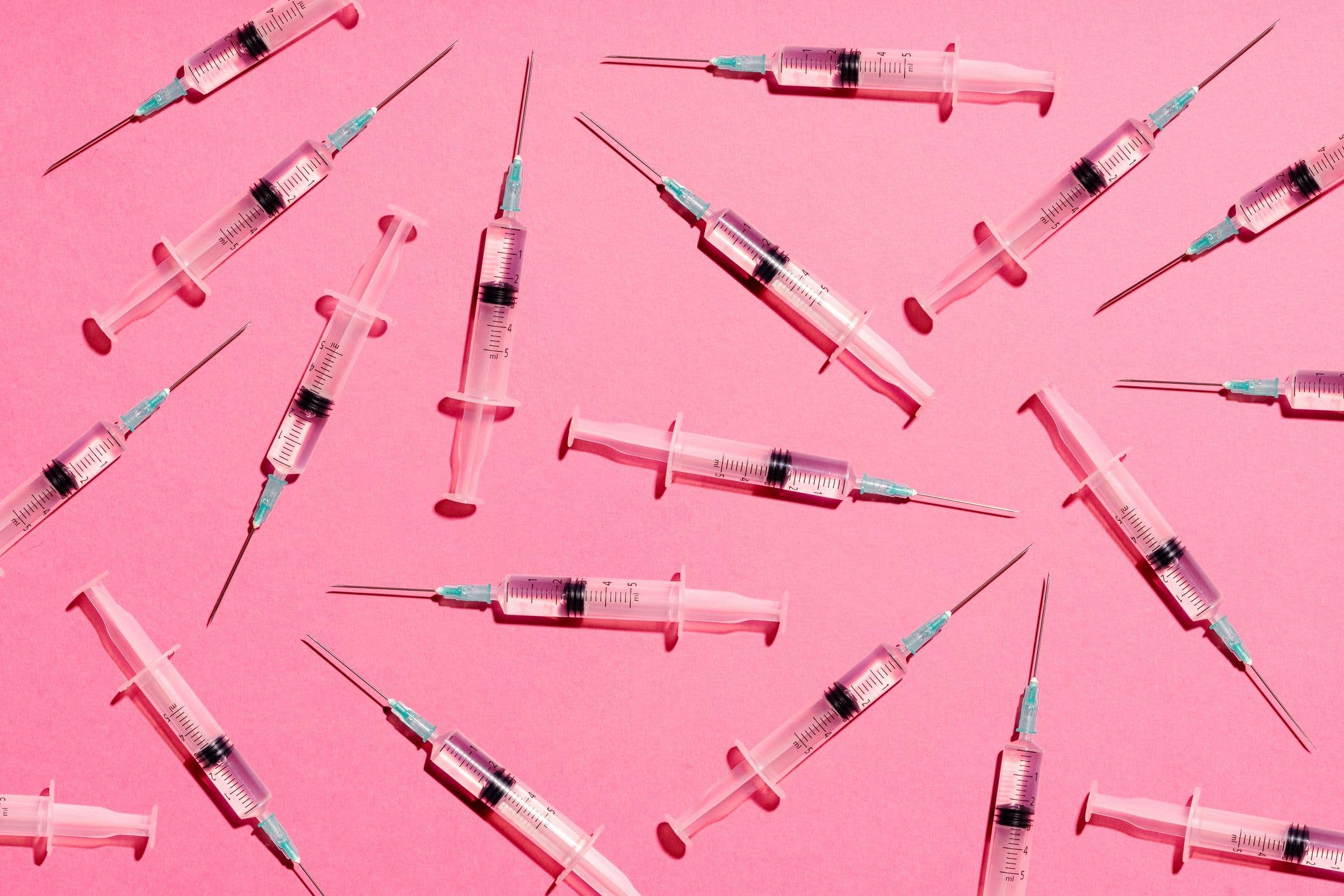 Syringe with injection or vaccine repetition pattern on pink background