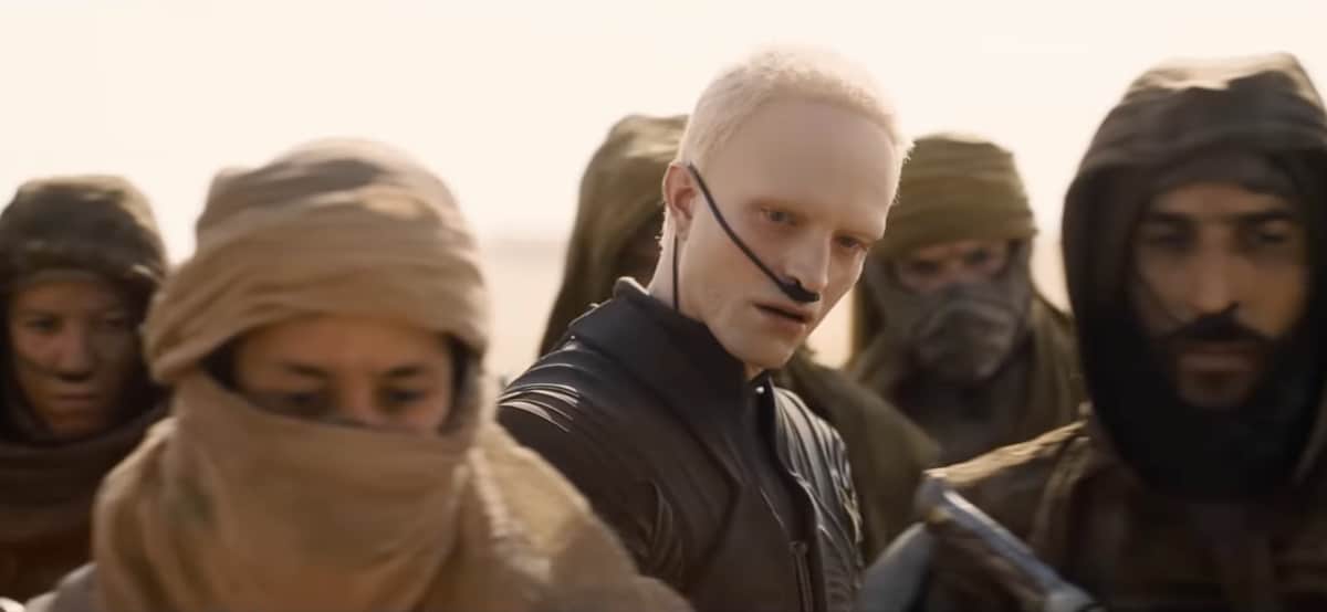 His look, bleached eyebrows, and buzzed blonde hair, is already drawing attention, but it’s the ambiguity of his character that stands out