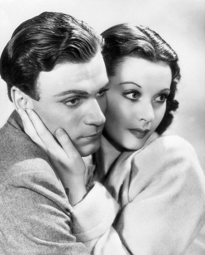 Vivien Leigh holds her palm against Laurence Olivier's cheek as they both look towards the frame's right side in a publicity shoot in 1939.