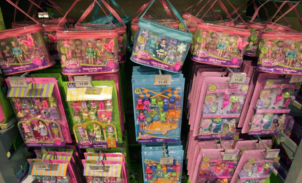 Polly Pocket toys hang in brightly coloured solid plastic packaging and zipped bags with dolls and accessories. 