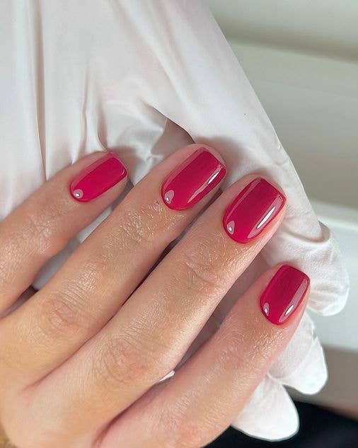 A timeless, vibrant red manicure on short, neat nails, offering a sophisticated and polished spring look.