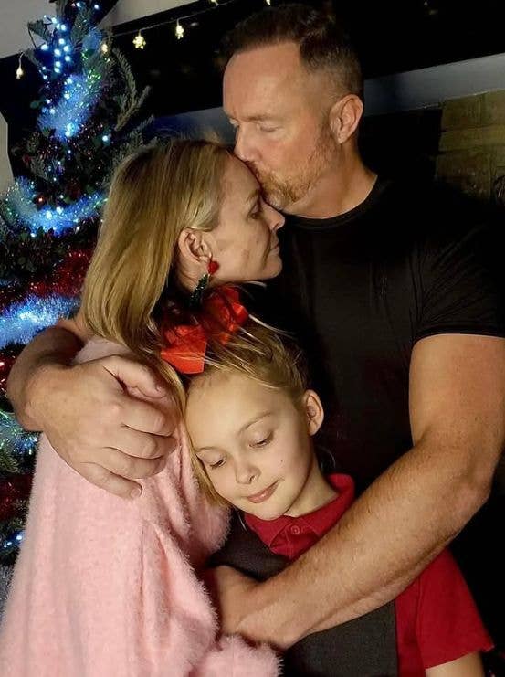 Mel Schilling being embraced by her husband and daughter