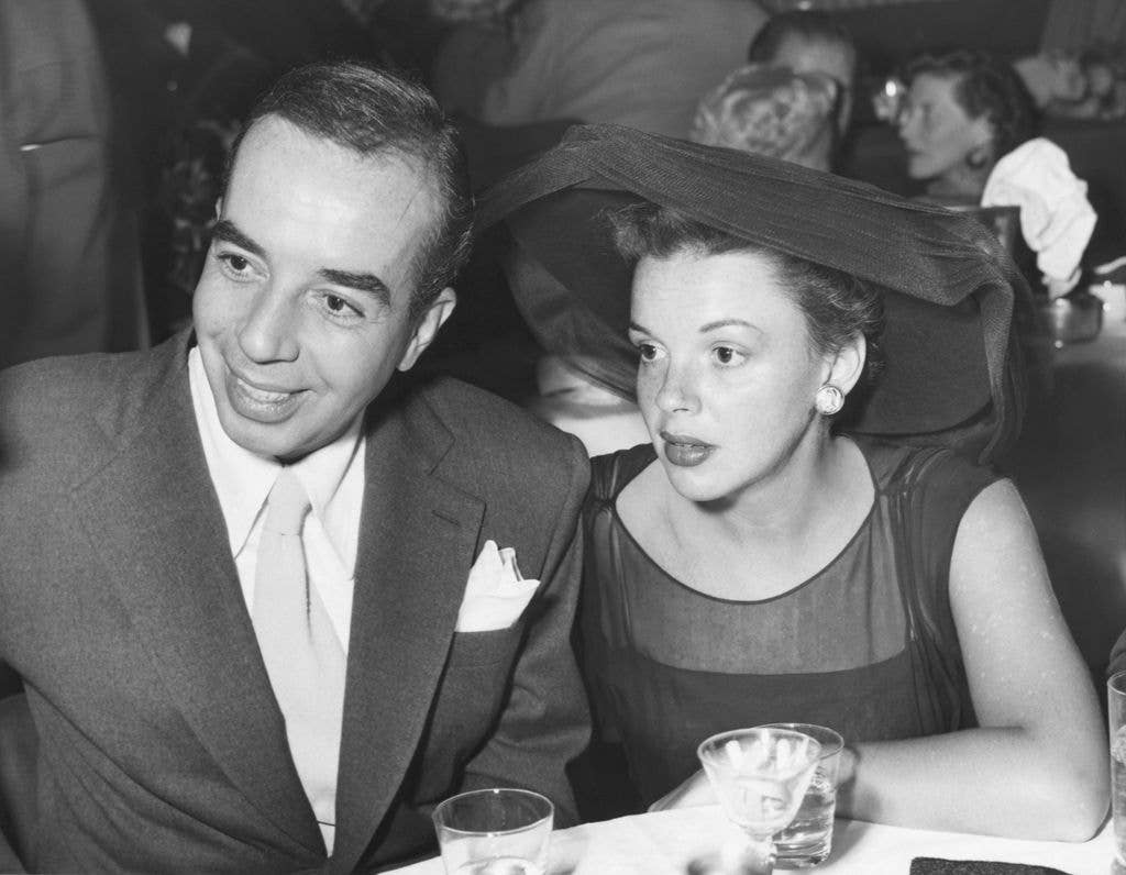 Vicente Minnelli and Judy Garland sit next to one another at a table.