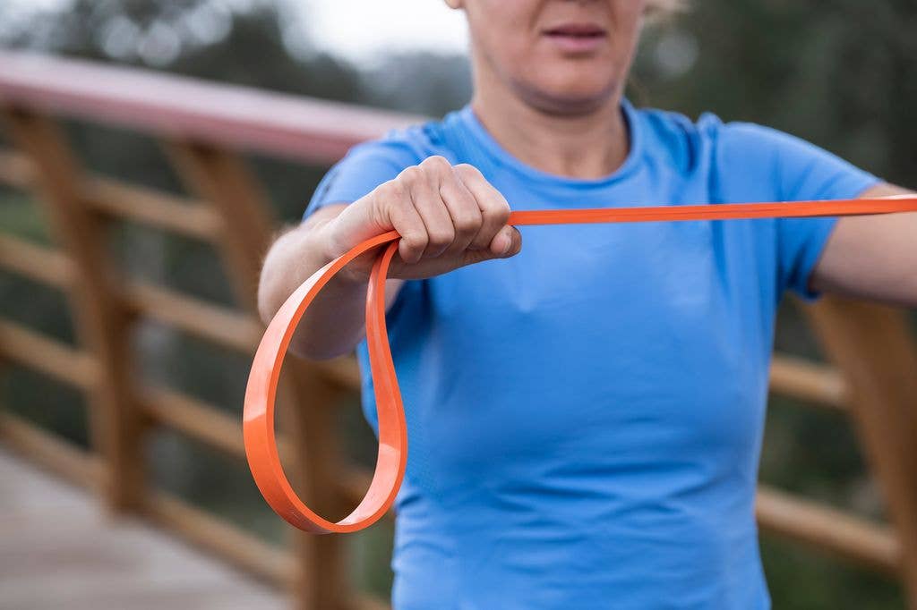 woman in blue t-shirt exercising with elastic band