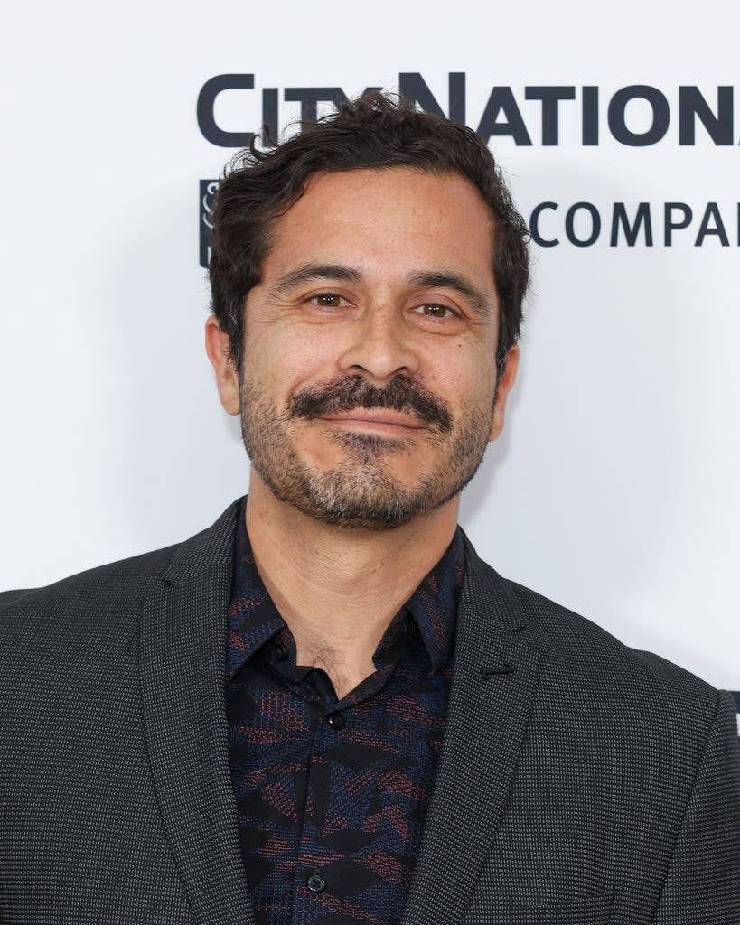 Headshot of Chris Pérez in a textured slate jacket and patterned burgundy and black shirt. 