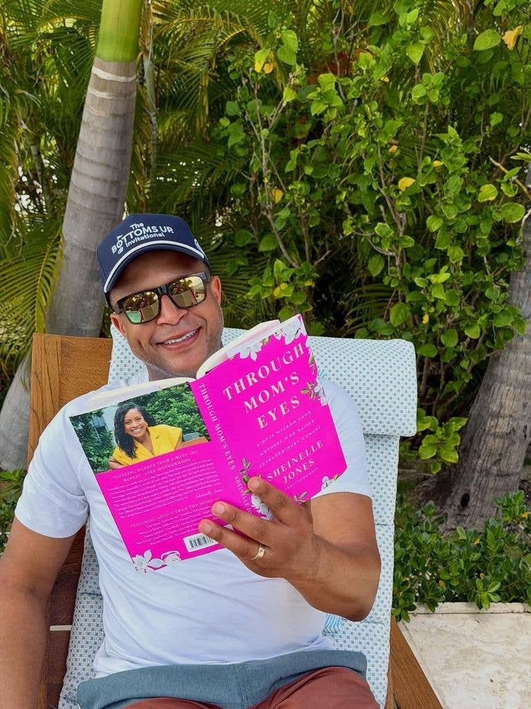 Craig reading a book dressed in shorts and white top