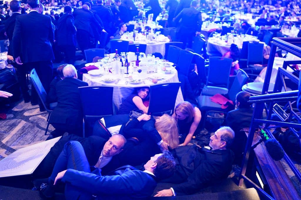 Attendees hide under tables after an  incident at the annual White House Correspondents Association Dinner