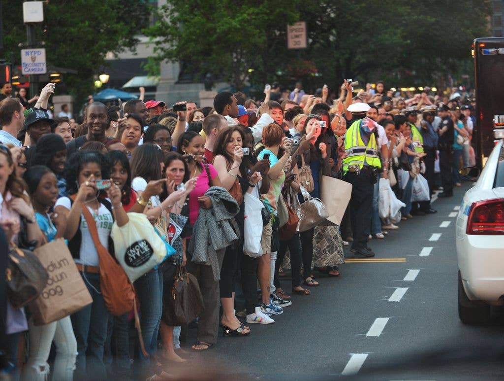 Passers-by line a street as the motorcade of US President Barack Obama passes by May 30, 2009 in New York City. President Barack Obama and First Lady Michelle Obama will be attending the Broadway show "Joe Turner's Come and Gone" at the Belasco.