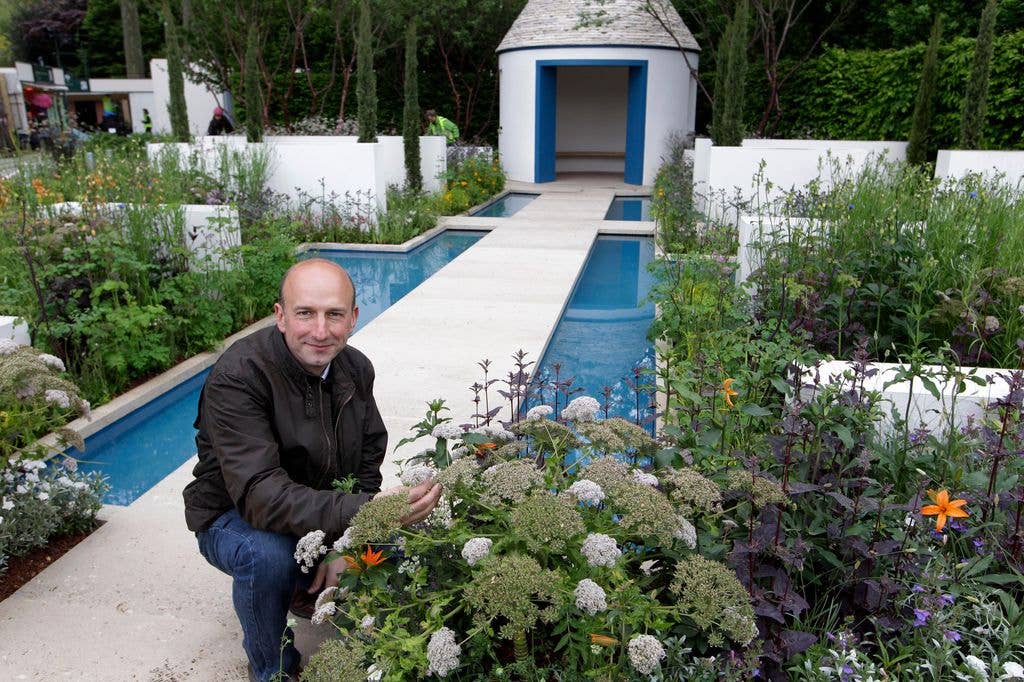 Garden designer Nigel Dunnett poses in his show garden 'the Royal Bank of Canada Blue Water Garden' during a built-up day of Chelsea Flower Show in London, Sunday, May 20, 2012. The show garden showcases inventive urban rainwater management in a wide-raging 10 year global commitment to help protect the world's most precious natural resource, water. After one of the soggiest springs in living memory, the world's most famous flower show opens this week. (AP Photo/Sang Tan)