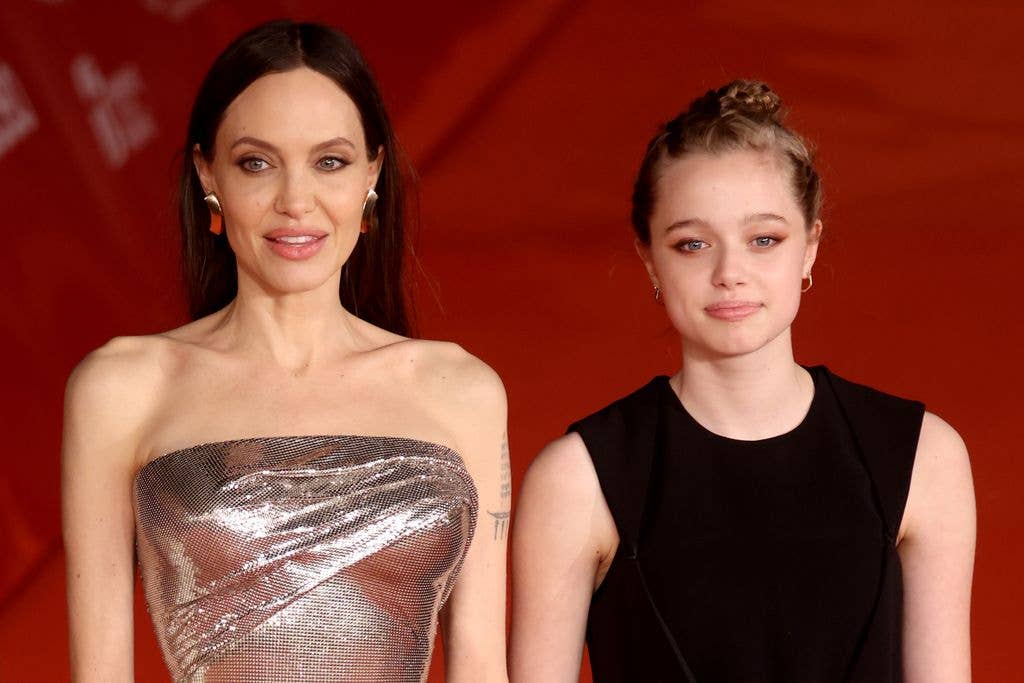 Angelina Jolie posing in a shiny silver dress and Shiloh Jolie Pitt next to her in a black dress 